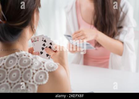 Zugeschnittenes Bild von Freundinnen, die zu Hause Karten spielen Stockfoto