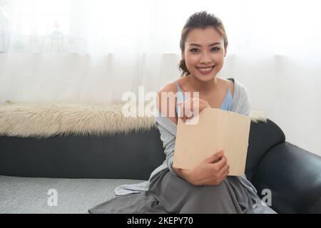 Porträt einer ziemlich lächelnden jungen Frau mit geöffnetem Buch Stockfoto