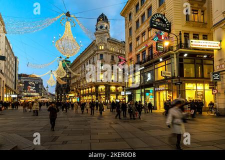 Menschen gehen auf der Abendstraße Graben - eine der wichtigsten und berühmten Fußgängerzonen in Wien, Österreich. Stockfoto