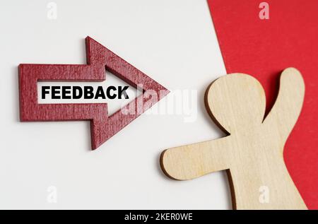 Wirtschafts- und Geschäftskonzept. Auf einer rot-weißen Oberfläche eine menschliche Figur und ein Pfeil mit der Aufschrift - FEEDBACK Stockfoto