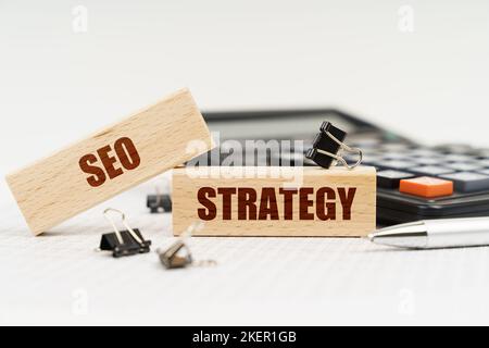 Geschäfts- und Finanzkonzept. Auf weißem Hintergrund ein Rechner, ein Stift, Berichte und Holzstempeln mit der Aufschrift - SEO-STRATEGIE Stockfoto