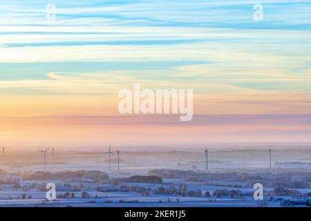 Windturbinen bei Sonnenuntergang in einer kalten Winterlandschaft Stockfoto