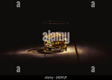 Glas Whiskey mit Eis auf einem Holztisch Stockfoto