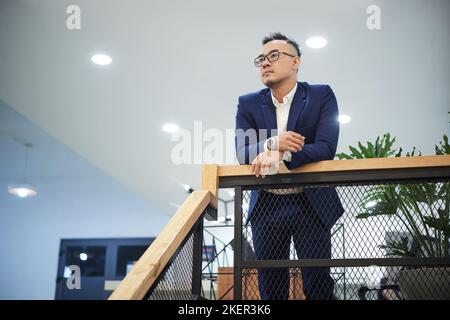 Nachdenklicher junger vietnamesischer Einsteiger in seinem modernen Büro Stockfoto