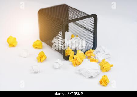 Office-Tools. Auf weißem Hintergrund ein Metallstift-Korb und zerknittertes gelbes und weißes Papier. Stockfoto