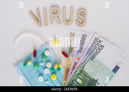 Die Inschrift Virus , Dollar, medizinische Maske, umgeben von Drogen und Pillen. Das Konzept der Medizin. Aufgenommen von oben auf weißem Hintergrund. Stockfoto