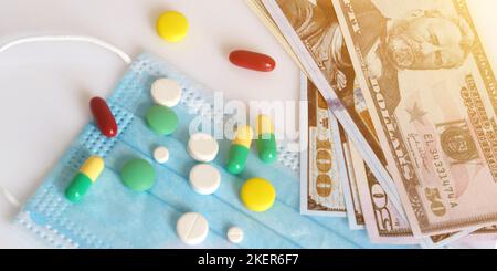 Dollar in einer medizinischen Maske, umgeben von Drogen und Pillen. Das Konzept von Medecine. Aufgenommen von oben auf weißem Hintergrund. Stockfoto