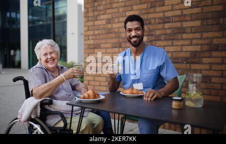 Pfleger beim Frühstück mit seinem Kunden im Café. Stockfoto