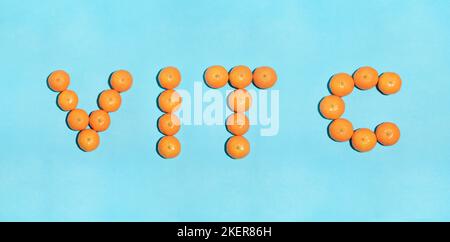 Saftige Mandarinen auf blauem Hintergrund bilden das Wort VIT C, wie Vitamin Stockfoto