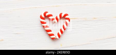 Flach Lay Weihnachtskomposition mit Zuckerstöcken in der Form oh Heart auf hellblauem Holzhintergrund. Stockfoto