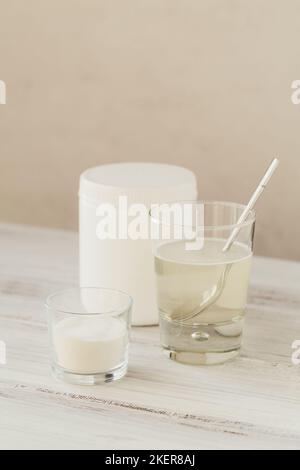 Glas mit in Wasser gelöstem Kollagen und Kollagenproteinpulver auf einem weißen Holztisch. Gesundes Lifestyle-Konzept. Stockfoto