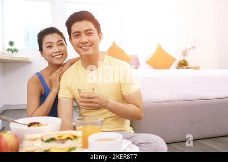 Portrait eines fröhlichen jungen asiatischen Paares beim Frühstück Stockfoto