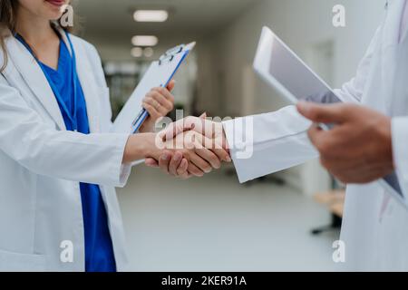 Nahaufnahme von Ärzten, die sich am Krankenhausflur die Hände schütteln. Stockfoto