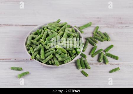 Komposition mit biologischem Tiefkühlgemüse auf weißem Holzhintergrund. Grüne Bohnen in einer Schüssel Stockfoto