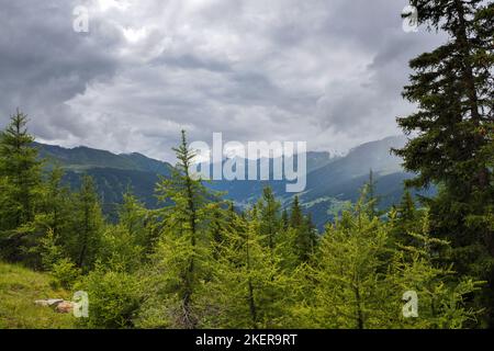 Gewitter Wolken über den Bergen. Grüne Wiesen, verstreute Siedlungen und dunkle Wälder unter beeindruckenden und interessanten Wolken. Stockfoto