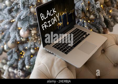 Black Friday Shopping-Konzept auf dem schwarzen Bildschirm des Laptops vor verschwommenem weihnachtslicht Hintergrund geschrieben Stockfoto