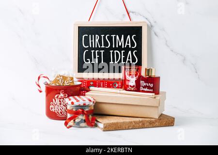 Geschenkideen für Weihnachten. Weihnachtsgeschenk für alle. Text Weihnachts-Geschenkideen auf schwarzem Brett und rot-brauner Zero Waste Cup, Einkaufstasche, Socken Stockfoto