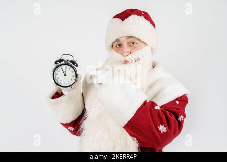 Weihnachten und Weihnachtskonzepte. Der Weihnachtsmann zeigt die verbleibende Zeit vor Weihnachten auf der Uhr an. Isoliert auf Weiß Stockfoto