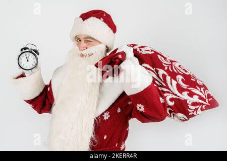 Weihnachten und Weihnachtskonzepte. Der Weihnachtsmann zeigt die verbleibende Zeit vor Weihnachten auf der Uhr an. Isoliert auf Weiß Stockfoto