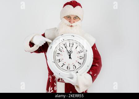 Weihnachten und Weihnachtskonzepte. Der Weihnachtsmann zeigt die verbleibende Zeit vor Weihnachten auf der Uhr an. Isoliert auf Weiß Stockfoto