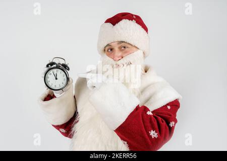 Weihnachten und Weihnachtskonzepte. Der Weihnachtsmann zeigt die verbleibende Zeit vor Weihnachten auf der Uhr an. Isoliert auf Weiß Stockfoto