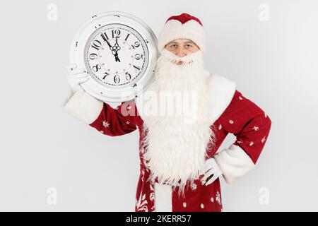 Weihnachten und Weihnachtskonzepte. Der Weihnachtsmann zeigt die verbleibende Zeit vor Weihnachten auf der Uhr an. Isoliert auf Weiß Stockfoto
