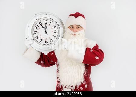 Weihnachten und Weihnachtskonzepte. Der Weihnachtsmann zeigt die verbleibende Zeit vor Weihnachten auf der Uhr an. Isoliert auf Weiß Stockfoto