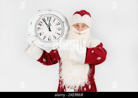 Weihnachten und Weihnachtskonzepte. Der Weihnachtsmann zeigt die verbleibende Zeit vor Weihnachten auf der Uhr an. Isoliert auf Weiß Stockfoto