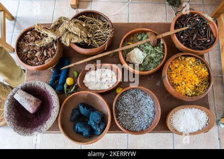 Eine Holzspindel liegt auf Schalen, die die Quellen für die natürlichen Farbstoffe enthalten, die in den besten Teppichen aus Teotitlan del Valle, Oaxaca, Mexiko, verwendet werden. Braun ist m Stockfoto