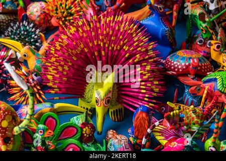 Bunt bemalte alebrijes aus kopalem Holz geschnitzt, die echte und mythische Kreaturen zum Verkauf in Oaxaca, Mexiko darstellen. Stockfoto