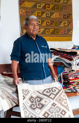 Der 84-jährige Weber Isaac Vasquez Garcia mit einem Wollteppich in Teotitlan, Oaxaca, Mexiko. Das Garn wird mit allen natürlichen Farbstoffen und Th gefärbt Stockfoto