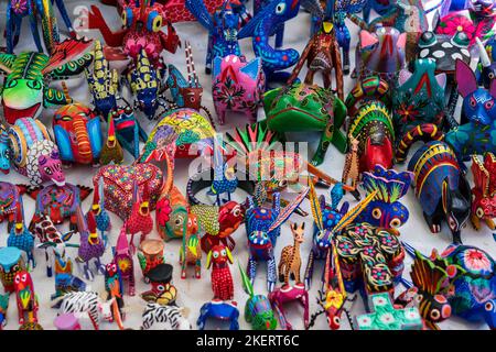 Bunt bemalte alebrijes aus kopalem Holz geschnitzt, die echte und mythische Kreaturen zum Verkauf in Oaxaca, Mexiko darstellen. Stockfoto