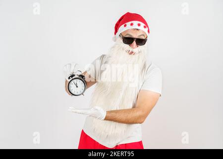 Weihnachten und Weihnachtskonzepte. Der Weihnachtsmann zeigt die verbleibende Zeit vor Weihnachten auf der Uhr an. Isoliert auf Weiß Stockfoto