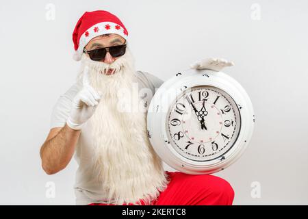 Weihnachten und Weihnachtskonzepte. Der Weihnachtsmann zeigt die verbleibende Zeit vor Weihnachten auf der Uhr an. Isoliert auf Weiß Stockfoto