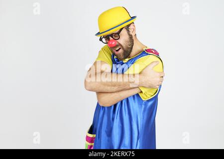 Urlaubskonzept. Clown in einem leuchtend blauen und gelben Anzug umarmt sich Stockfoto