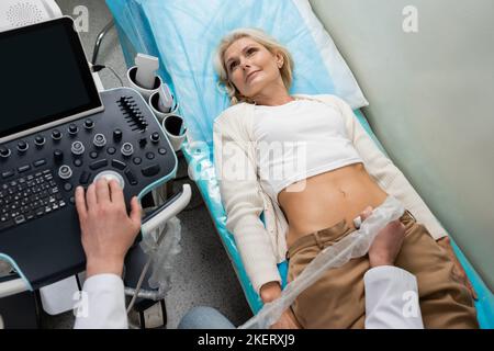 High-Angle-Ansicht des Arztes, der Abdominalsonographie der lügenden Frau macht, Stockbild Stockfoto