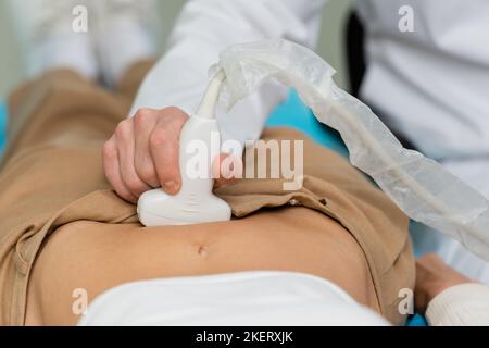 Teilansicht des Arztes, der abdominale Ultraschalldiagnostik der Frau macht, Stockbild Stockfoto