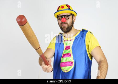Urlaubskonzept. Der Clown ist ein Mann in einem leuchtend blauen und gelben Anzug mit einem Baseballschläger. Stockfoto