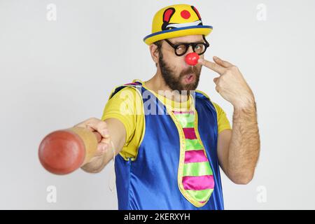 Urlaubskonzept. Der Clown ist ein Mann in einem leuchtend blauen und gelben Anzug mit einem Baseballschläger. Stockfoto