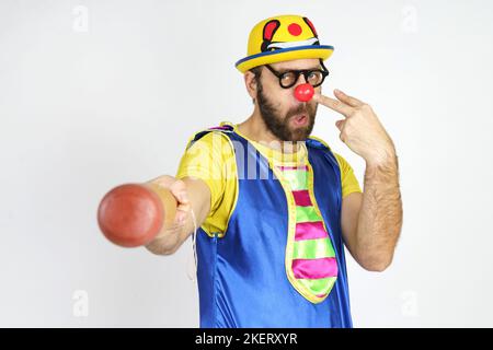 Urlaubskonzept. Der Clown ist ein Mann in einem leuchtend blauen und gelben Anzug mit einem Baseballschläger. Stockfoto