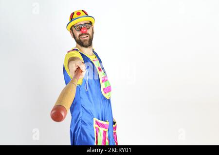 Urlaubskonzept. Der Clown ist ein Mann in einem leuchtend blauen und gelben Anzug mit einem Baseballschläger. Stockfoto