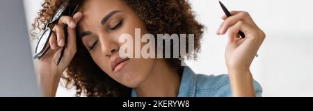 Müde afroamerikanische Frau mit geschlossenen Augen halten Brille und Stift, Banner, Stock Bild Stockfoto