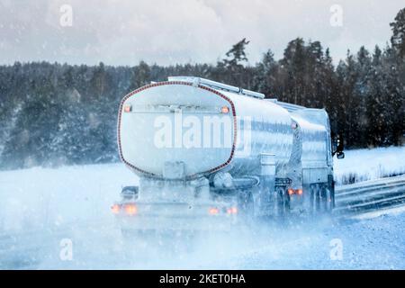 Rückansicht eines Tankers, der an einem Wintertag bei starkem Schneefall die Autobahn entlang fährt. Stockfoto