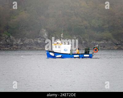 Fischer werfen Fallen von kleinen Arbeitsbooten aus, im Nebel, nahe der felsigen Küste entlang des Firth of Clyde, Schottland, Großbritannien. Stockfoto