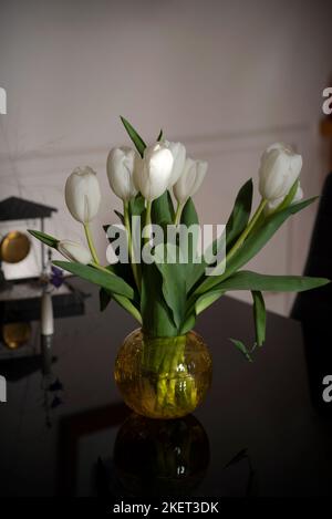 Schöne weiße Tulpen in einer Glasvase auf dem Tisch Stockfoto
