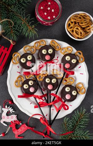 Süße Idee Weihnachtsgeschenke - Cake Pops Weihnachtsmann Rentiere aus Cookies in Schokolade und Cracker auf weißem Teller, Draufsicht Stockfoto