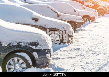 Autos mit Schnee bedeckt auf einem Parkplatz im Wohngebiet Stockfoto