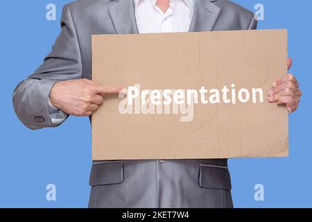 Der Mann hält in der Hand ein Pappblatt mit einer grob gemalten Inschrift "Präsentation" und zeigt darauf mit seinem Finger, isoliert auf blauem Hintergrund Stockfoto