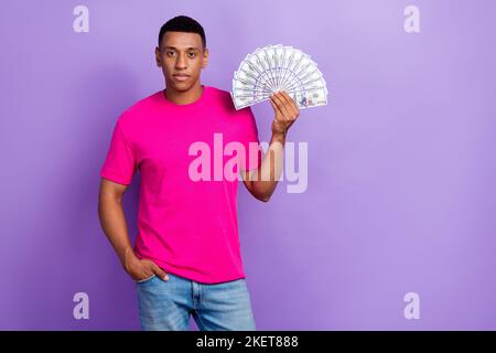 Foto von jungen reichen erfolgreichen ernsthaften Geschäftsmann halten viel Geld Stapel Dollar Startup funktioniert guten Markt erhöhen isoliert auf pastellviolette Farbe Stockfoto