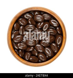 Mokka-Bohnen aus dunkler Schokolade, in einer Holzschüssel. Bonbons aus einer Mischung aus Kaffeebohnen-Geschmack mit dunkler Schokolade, in Form von Kaffeebohnen. Stockfoto